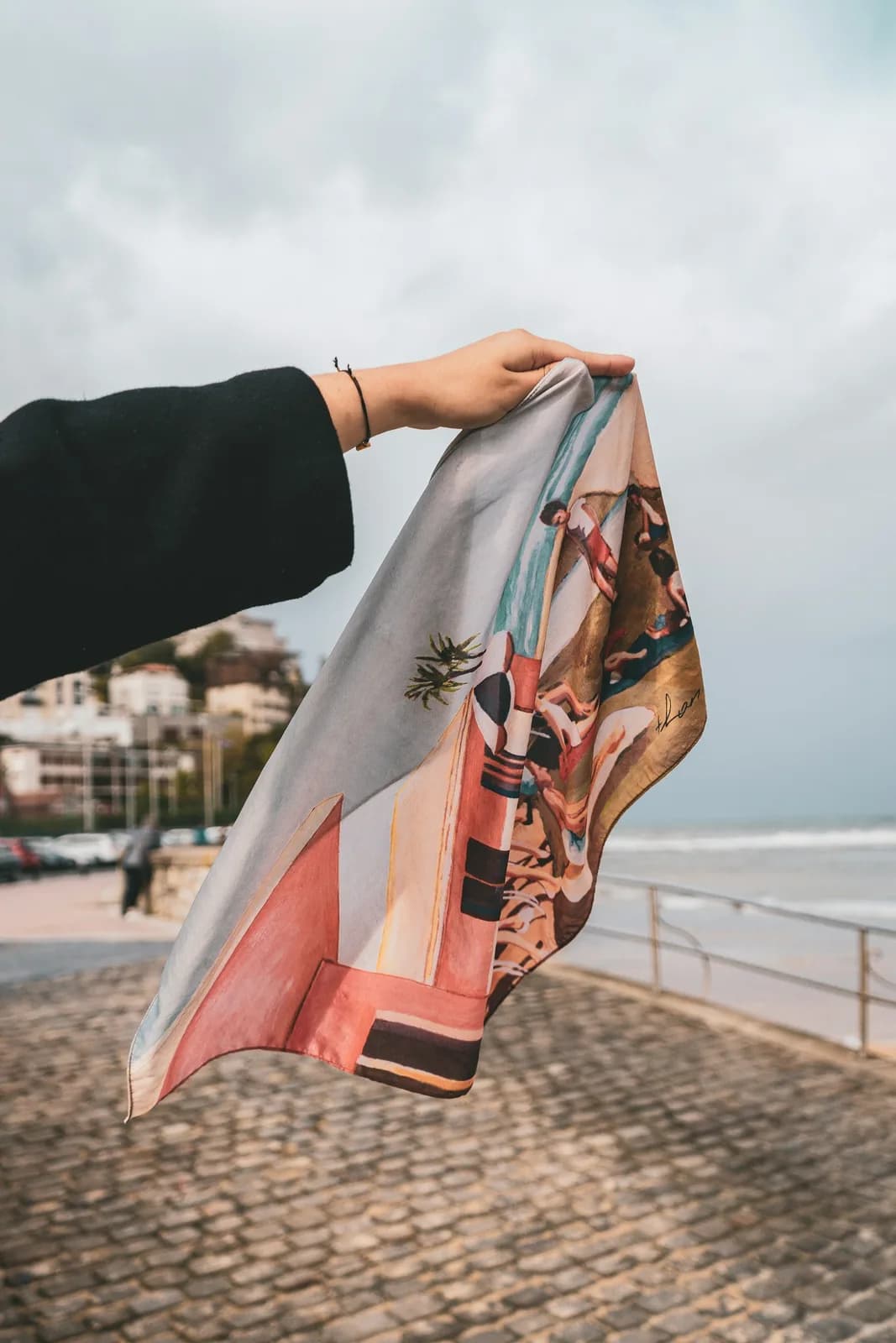 Printed silk scarf, Riviera print, held against the sky